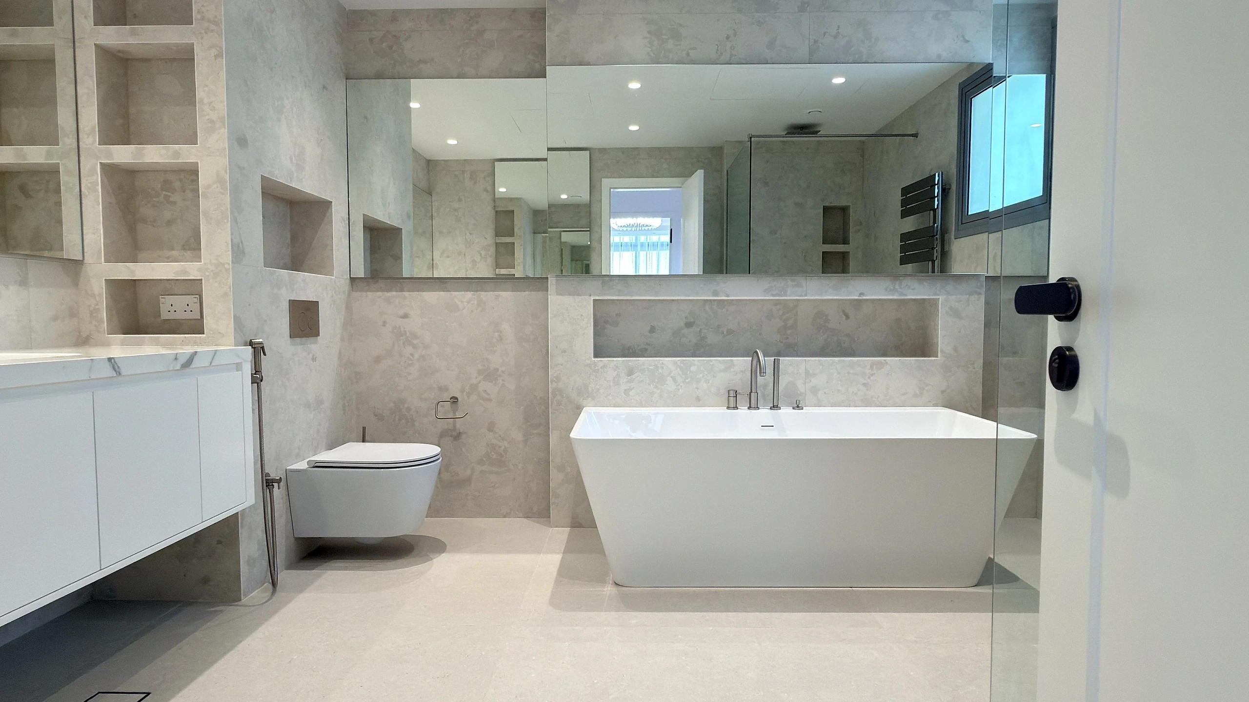 Bathroom fit-out in Dubai with freestanding bath, stone cladding and fitted vanity
