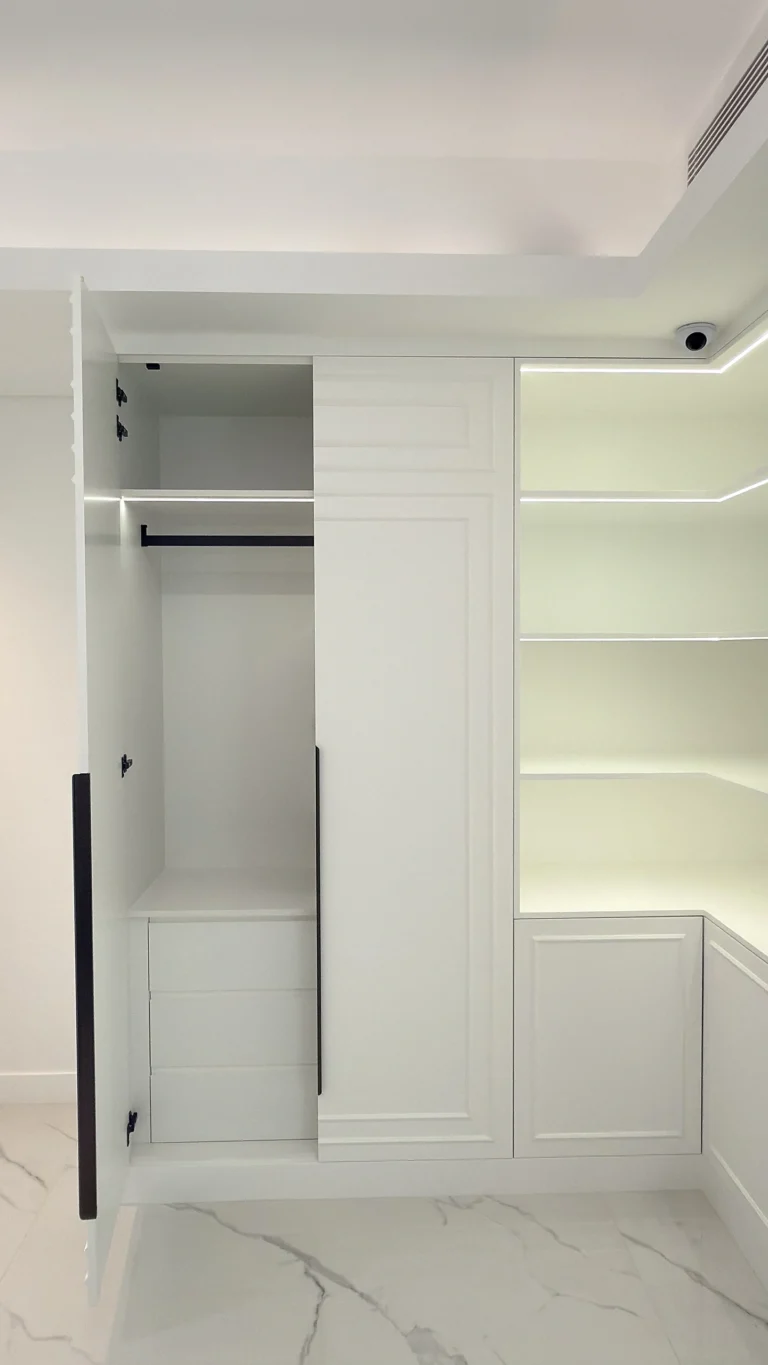 Fitted white wardrobe in Dubai with hanging rail and integrated corner shelving