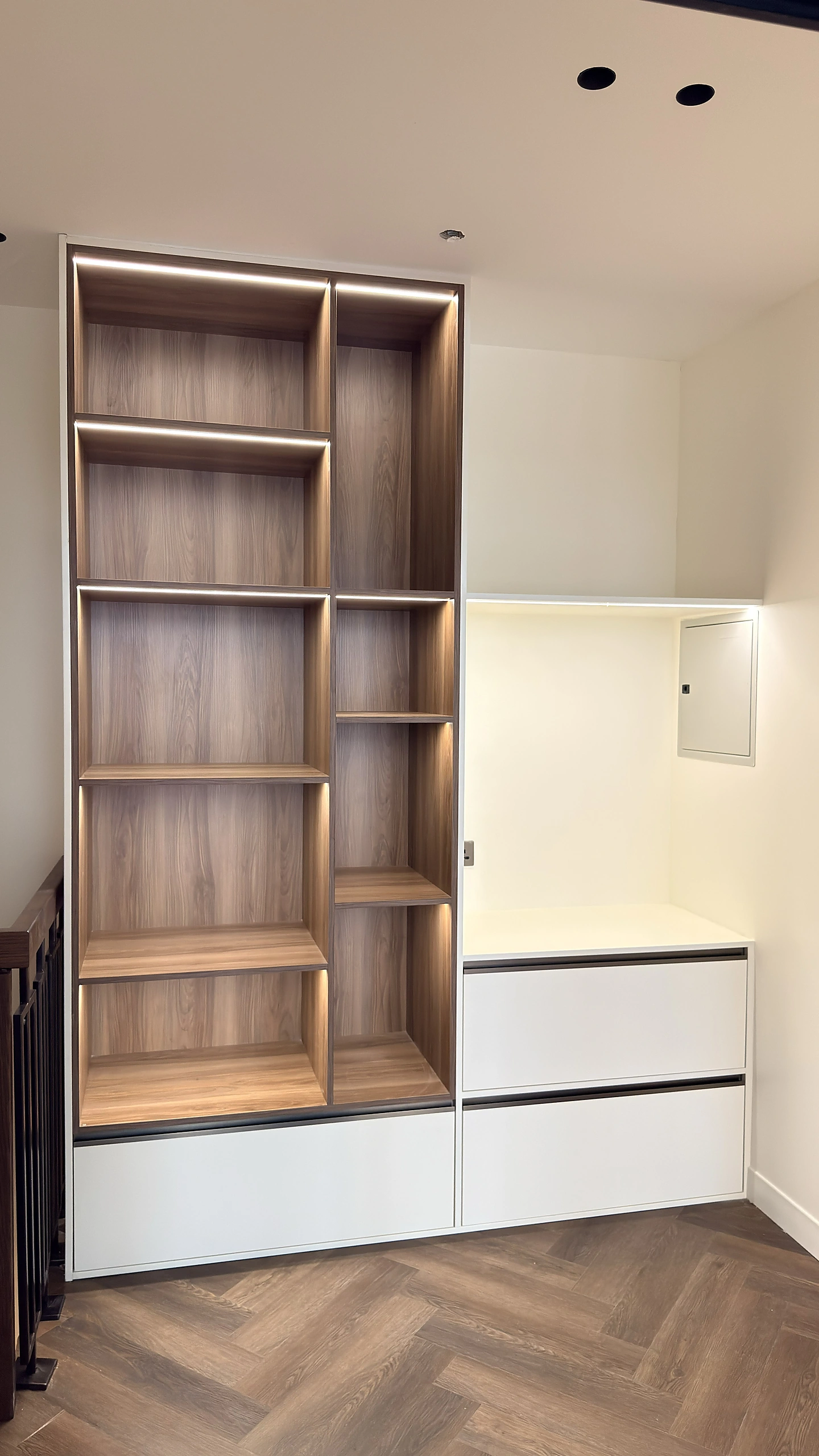 Bespoke bookshelf in Dubai in walnut Egger board with integrated LED shelving and a white drawer bank