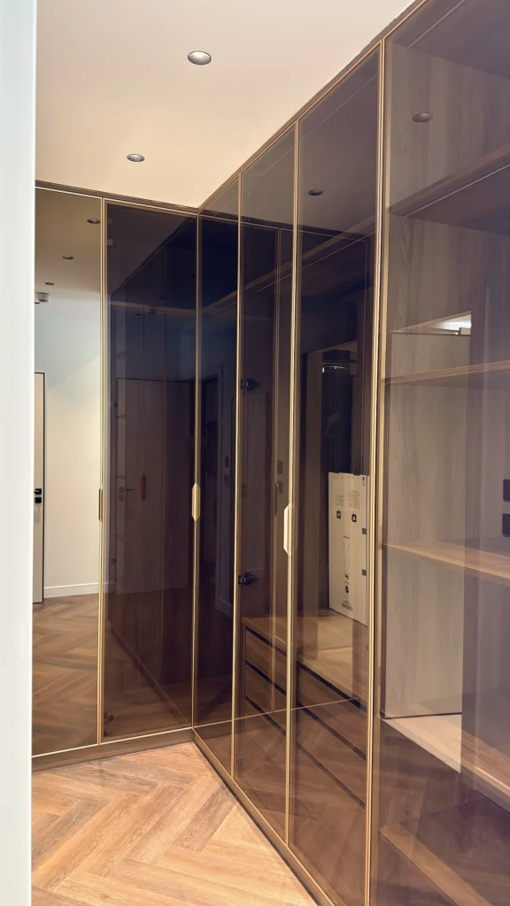 Walk-in wardrobe in Dubai with bronze glass doors and brushed brass framing